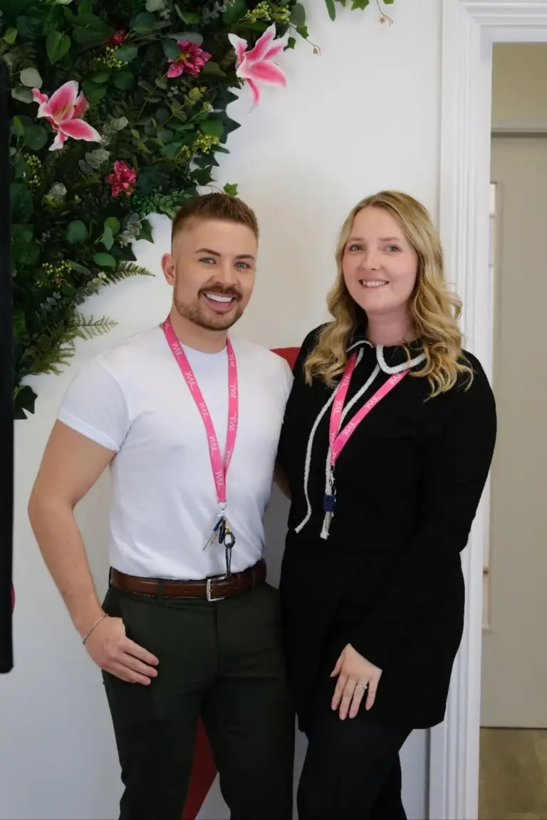 Luke and Katie standing in front of a floral background